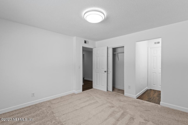 unfurnished bedroom with a textured ceiling, dark carpet, and a closet