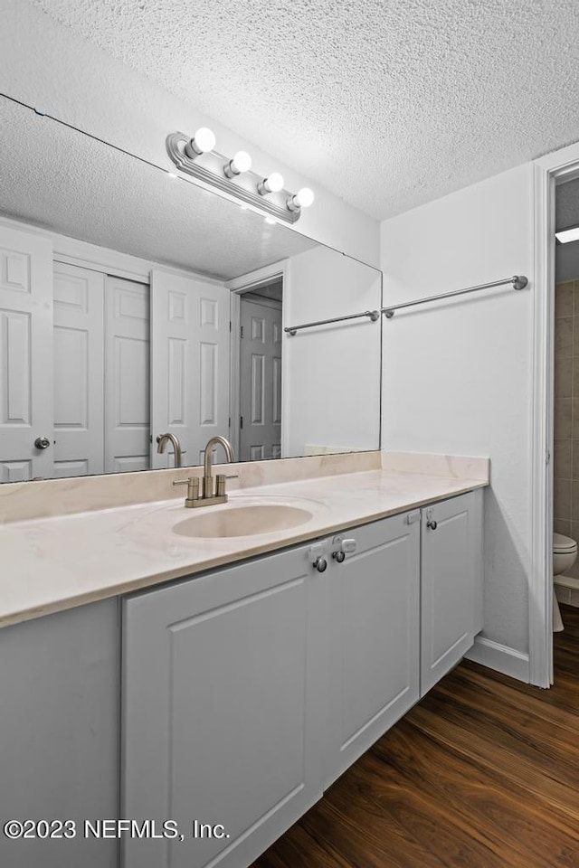 bathroom featuring vanity, hardwood / wood-style floors, toilet, and a textured ceiling