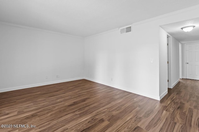 spare room featuring dark wood-type flooring and crown molding