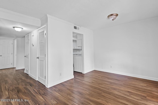 spare room featuring washer / clothes dryer, crown molding, and dark hardwood / wood-style flooring