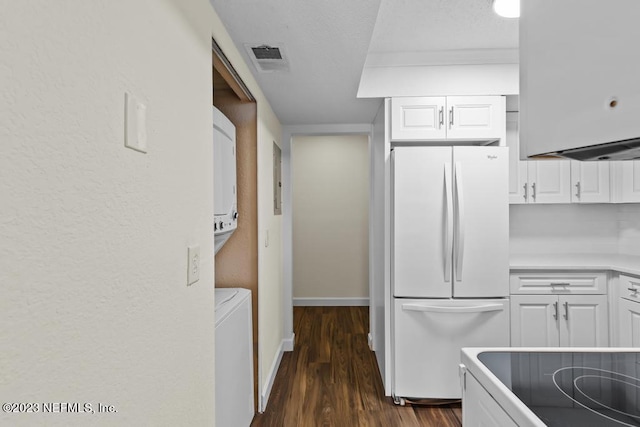 kitchen featuring white cabinetry, dark wood-type flooring, white fridge, and stacked washer and dryer