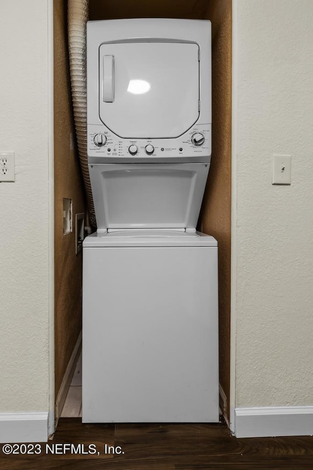 washroom with stacked washer / drying machine and hardwood / wood-style floors