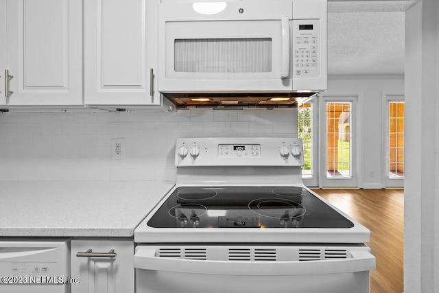 kitchen with light stone counters, white appliances, backsplash, white cabinetry, and light wood-type flooring