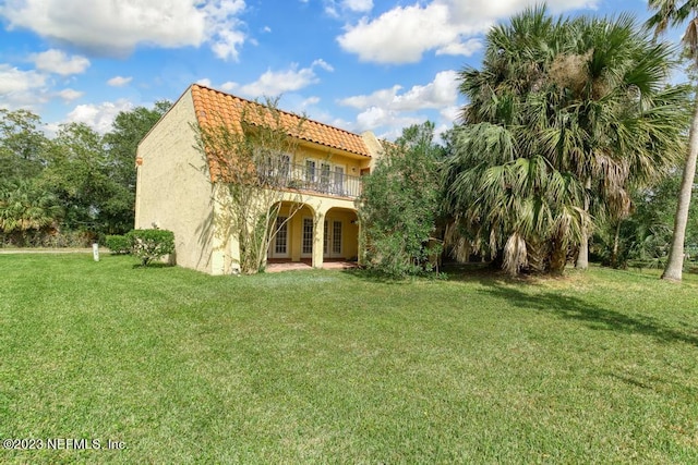 back of property with a yard and a balcony