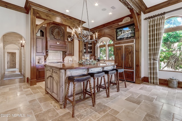 kitchen featuring pendant lighting, crown molding, a kitchen island, and a wealth of natural light