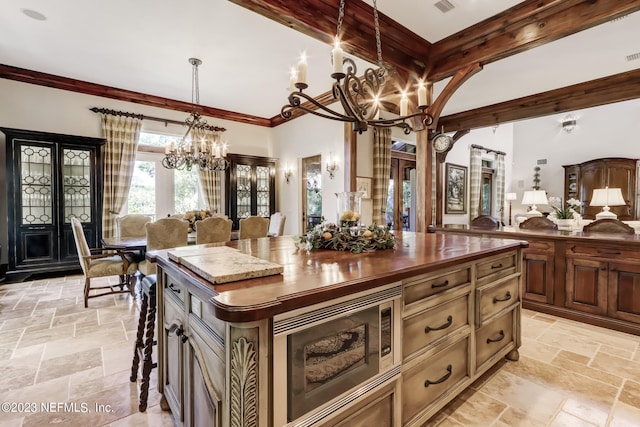 kitchen featuring a chandelier, pendant lighting, crown molding, stainless steel microwave, and a center island