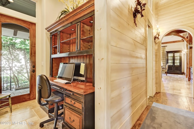 office area featuring a healthy amount of sunlight, built in desk, and wood walls