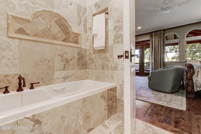 bathroom with plenty of natural light, a relaxing tiled tub, and wood-type flooring