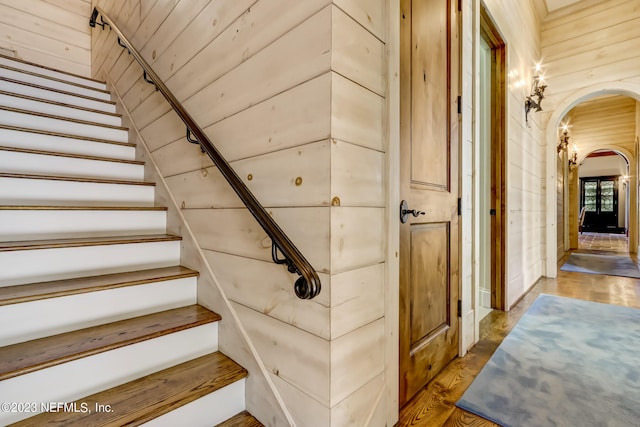 stairway with wood walls and hardwood / wood-style flooring