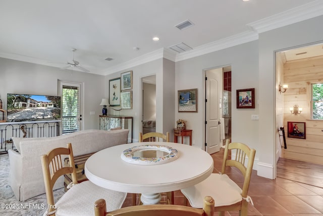 dining area with ceiling fan, wooden walls, ornamental molding, and tile patterned floors