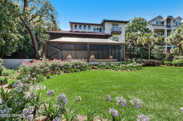 rear view of property with a yard, a sunroom, and a balcony