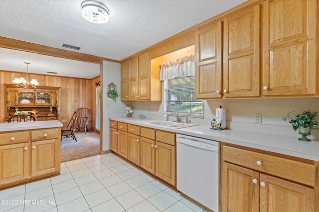 kitchen featuring wood walls, decorative light fixtures, sink, dishwasher, and light tile patterned floors