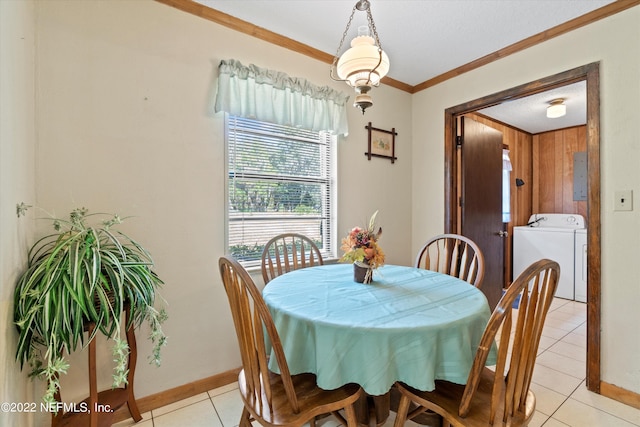 tiled dining area with crown molding and independent washer and dryer