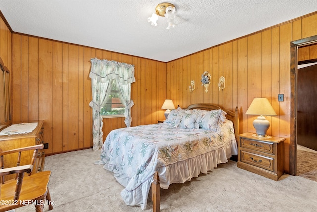 bedroom with light colored carpet, a textured ceiling, and wooden walls