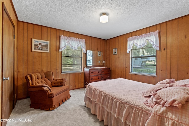 carpeted bedroom featuring a textured ceiling, wooden walls, and multiple windows