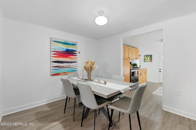 dining area featuring light wood-type flooring and ornamental molding