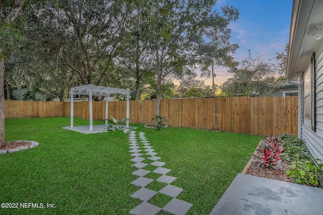 yard at dusk featuring a pergola