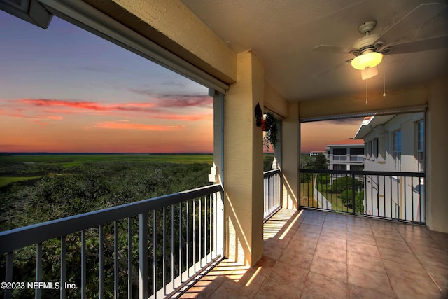 balcony at dusk with ceiling fan and a rural view