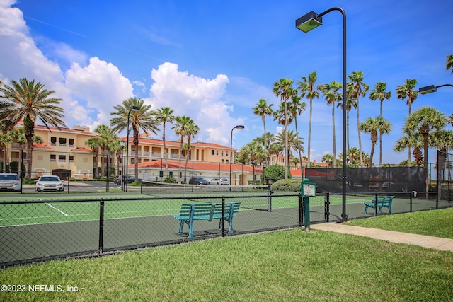 view of tennis court featuring a yard