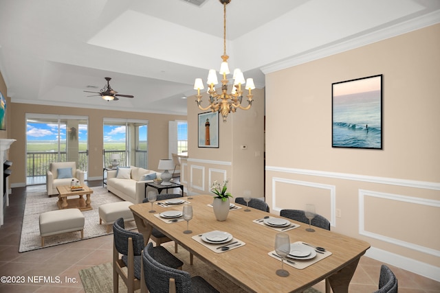 tiled dining area with a raised ceiling, ornamental molding, and ceiling fan with notable chandelier