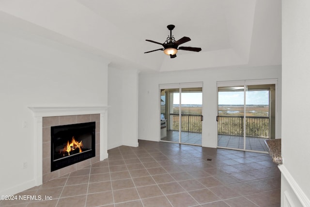 unfurnished living room featuring light tile patterned floors, a tile fireplace, a raised ceiling, and ceiling fan