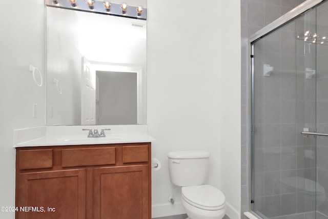 bathroom featuring vanity, a shower with door, and toilet