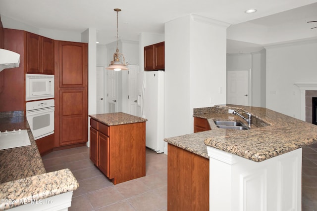 kitchen with sink, white appliances, a fireplace, decorative light fixtures, and tile patterned floors