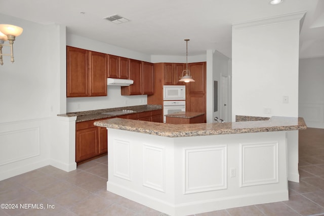 kitchen featuring pendant lighting, white appliances, light stone countertops, light tile patterned flooring, and kitchen peninsula