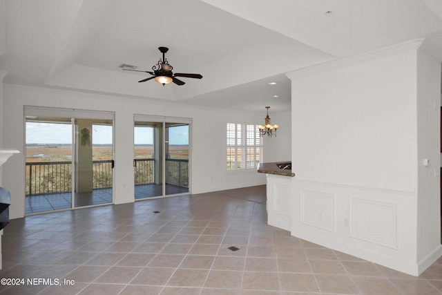 tiled spare room featuring ornamental molding, a tray ceiling, and ceiling fan with notable chandelier