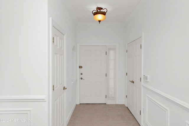 doorway with crown molding and light tile patterned flooring