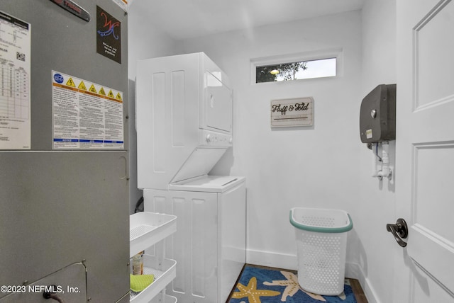 laundry area featuring heating unit and stacked washer and clothes dryer