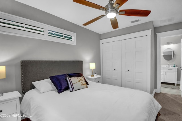 carpeted bedroom featuring sink, a closet, ensuite bathroom, and ceiling fan