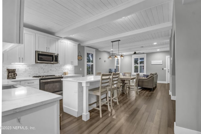 kitchen featuring white cabinetry, decorative backsplash, appliances with stainless steel finishes, and hanging light fixtures