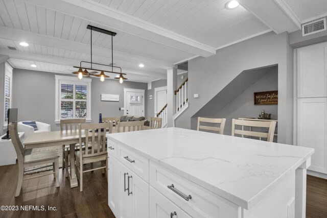 kitchen with beam ceiling, dark wood-type flooring, a kitchen island, and pendant lighting