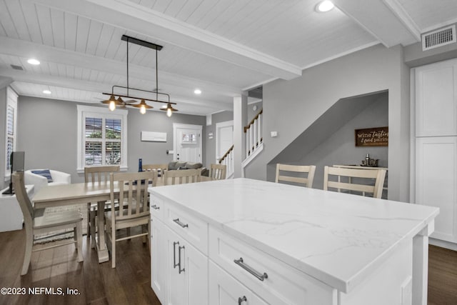 kitchen featuring pendant lighting, a center island, light stone counters, dark hardwood / wood-style flooring, and beamed ceiling