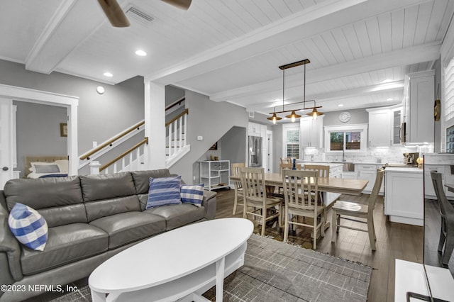 living room featuring ceiling fan, dark wood-type flooring, sink, and beam ceiling