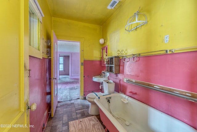 bathroom featuring sink, a bath, and toilet