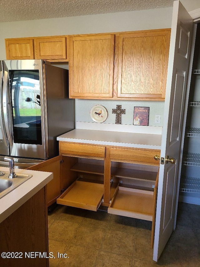 kitchen featuring dark tile patterned flooring, a textured ceiling, and stainless steel refrigerator