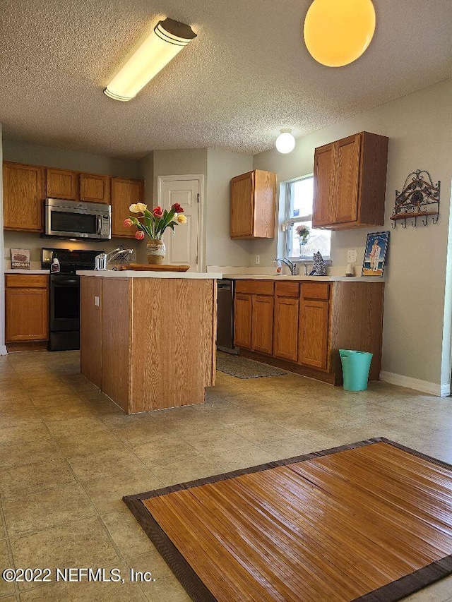 kitchen with a textured ceiling, a center island, and black appliances