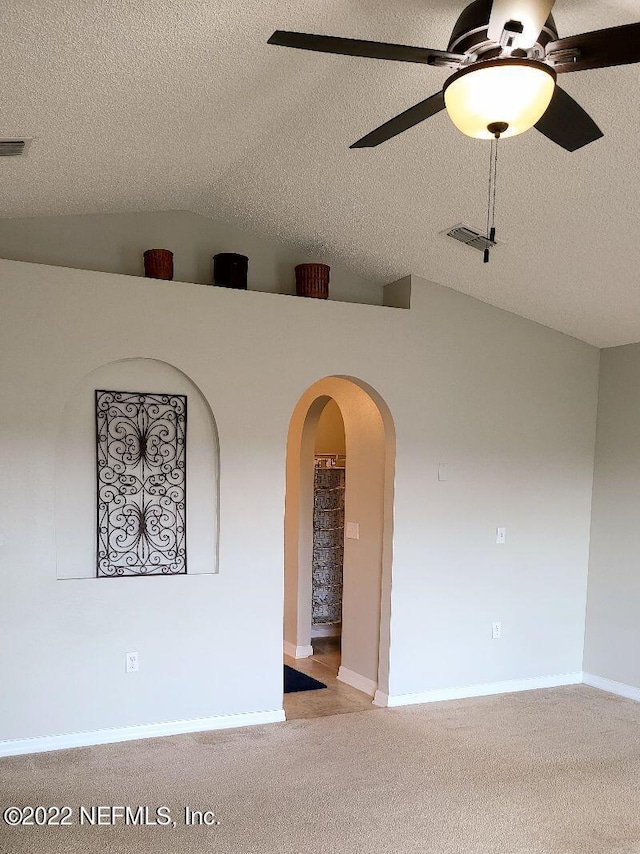 spare room with lofted ceiling, ceiling fan, light carpet, and a textured ceiling