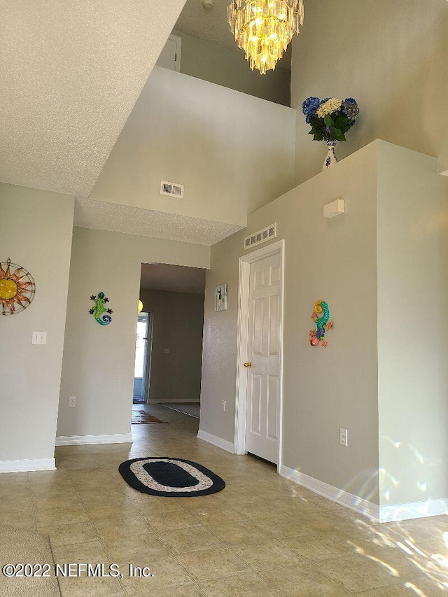 foyer with a high ceiling, a textured ceiling, and a notable chandelier