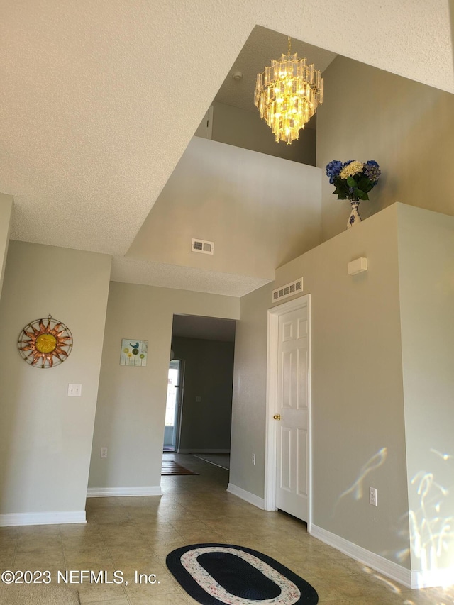 interior space featuring a textured ceiling, a high ceiling, and an inviting chandelier