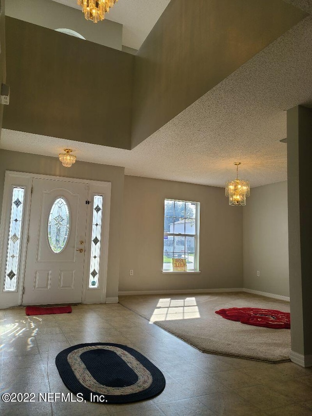 foyer with a textured ceiling, light carpet, and an inviting chandelier