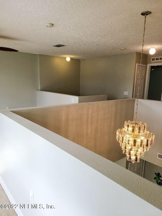 hall featuring a textured ceiling and an inviting chandelier