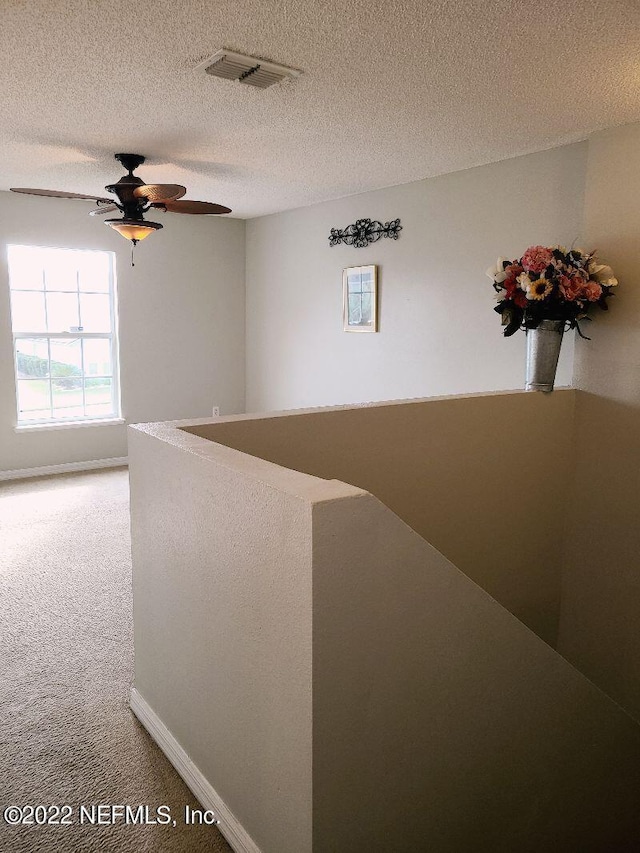 corridor with carpet flooring and a textured ceiling