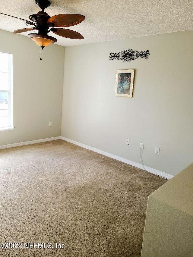 carpeted spare room with ceiling fan and a textured ceiling