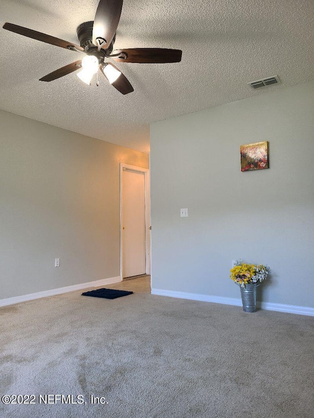 spare room with a textured ceiling, carpet floors, and ceiling fan