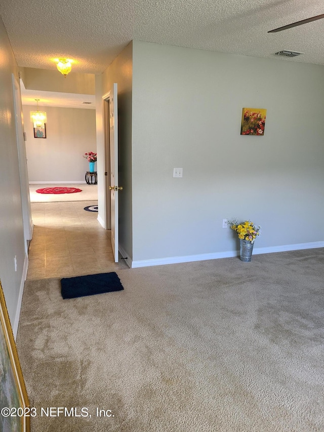 corridor with light carpet and a textured ceiling