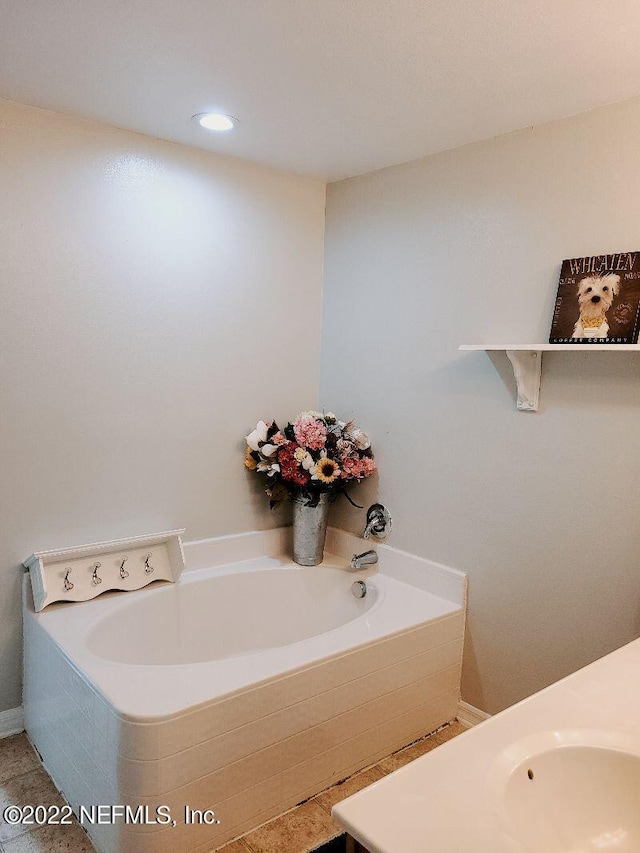 bathroom featuring a relaxing tiled tub, tile patterned floors, and sink