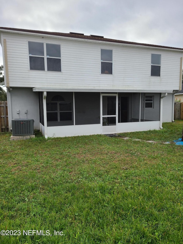 rear view of property with central air condition unit and a lawn